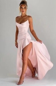 Woman wearing a pink one-shoulder dress with a high slit on a gray background