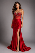 Woman wearing a red evening gown with a high slit on a gray background