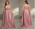 A plus-size model is shown wearing a dusty pink floor-length formal gown from the front and back against a neutral studio backdrop. The dress features a lace V-neck bodice, a beaded waistband, and an open lace-up back.